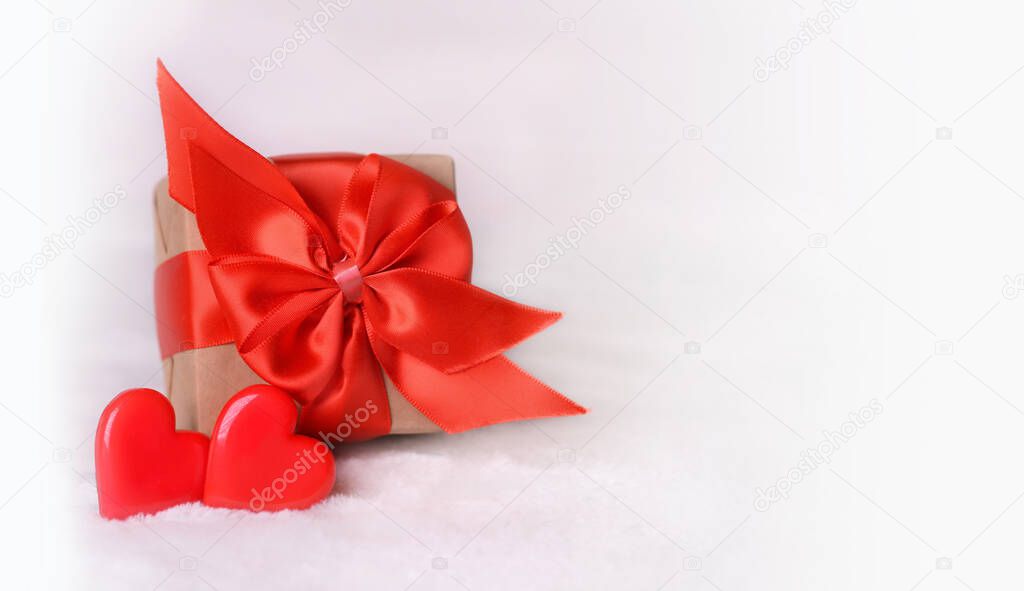 Valentine's Day background. Gift box with a red bow and two hearts on a white background. Valentines day concept.Copy space.