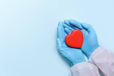 Tıp eldivenli bir doktorun iki eli, doktorların kalp ya da kardiyoloji hastalığı olan hastaları tedavi edip tedavi etmesi için kırmızı bir kalp taşıyor. Bağış konsepti. Boşluğu kopyala