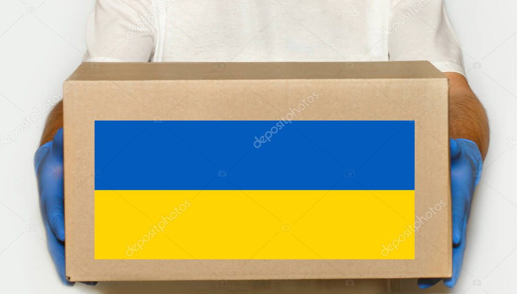 A volunteer holds a box of aid for Ukrainian refugees and poor citizens who find themselves in a war between Ukraine and Russia.Humanitarian aid concept.Donate for refugees