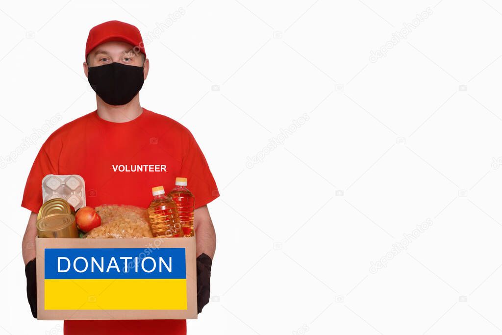 A volunteer holds a box of aid for Ukrainian refugees and poor citizens who find themselves in a war between Ukraine and Russia.Humanitarian aid concept.Donate for refugees. Copy space.