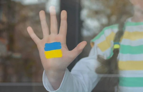 Mała Dziewczynka Stoi Przy Oknie Swojego Domu Pomalowaną Flagą Ukrainki — Zdjęcie stockowe