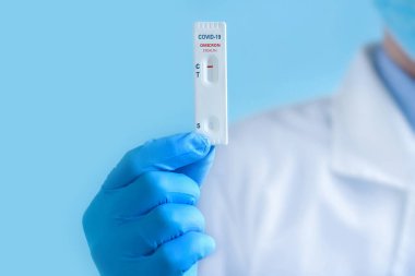 Koruyucu maske ve eldiven takan bir doktor yeni koronavirüse karşı IgM ve IgG antikorlarını tespit etmek için COVID-19 Omicron Stealth varyant türü için hızlı bir laboratuvar testi gösteriyor. Olumsuz sonuç.