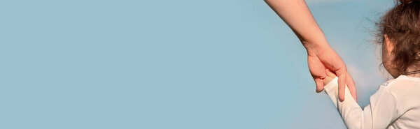 Папа держит ребёнка за руку на голубом небе. Баннер. Копирование пространства