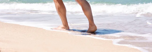 Male feet step on the sea wave. Summer vacations concept.Beach holiday. Banner. Copy space