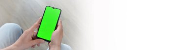 Adamın biri elinde yeşil ekranlı akıllı telefon tutuyor. Mockup.Mockup. Uzayı metin için kopyala. Pankart