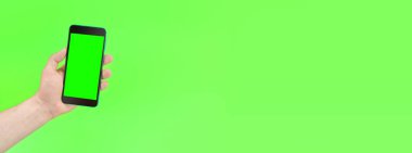 Yeşil arka planda yeşil ekranlı akıllı telefonu olan bir adam. Mockup.Mockup. Uzayı metin için kopyala. Pankart