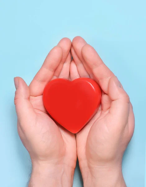 Red heart in man\'s hands isolated on blue background. Healthcare and hospital medical concept. Symbolic of Valentine day.Top view with space for text.