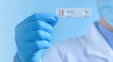 A doctor or nurse wearing a protective mask and gloves shows a rapid laboratory Express test for Langya henipavirus (LayV) to detect IgM and IgG antibodies to the Langya henipavirus. Negative result