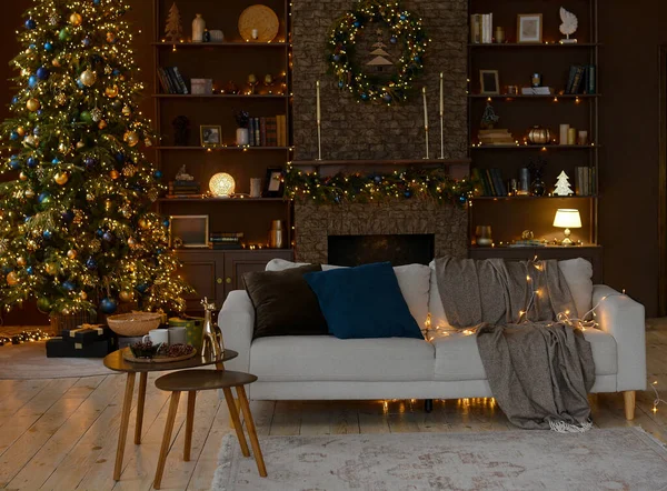 Noel ağacı, şömine ve büyük bir kitaplıkla süslenmiş güzel bir kanepesi olan modern bir oturma odası. Noel süslemeleri..
