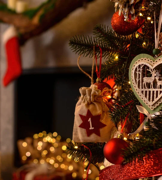 Advent calendar in the form of an eco bag hangs on the Christmas tree against the background of the Christmas room with a fireplace and Santa\'s boots.Christmas background. Advent calendar.