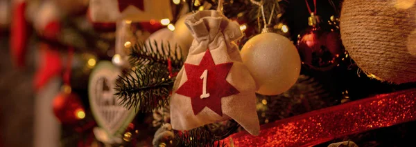 Advent calendar in the form of an eco bag hangs on the Christmas tree against the background of the Christmas room with a fireplace and Santa\'s boots.Christmas background. Advent calendar.