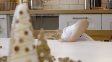 Masada Noel süsleri ve ağaç dallarıyla küçük şirin bir kız oturuyor. Noel kurabiyesi. Yılbaşı şekerleri Noel ağacının dalları.