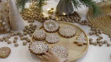 Anne ve çocuklar mutfakta Noel kurabiyesi süslerler. Bir erkek ve bir kız, kurabiyelerin üzerine şeker kremalı korselerle resim yapıyorlar. Yılbaşı şekerleri Noel ağacının dalları.