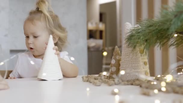 Een Schattig Klein Meisje Zit Aan Tafel Met Kerstversiering Tak — Stockvideo