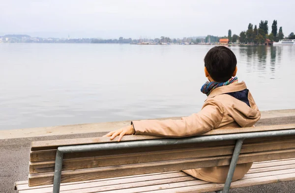Olgun bir kadın gölün önündeki bankta oturuyor bulutlu gökyüzü yalnızlık ve nostalji ile ufka bakıyor..