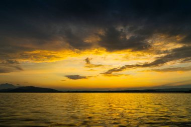 İsviçre 'nin Zugersee kasabasındaki Zug Gölü' nün gün batımında gökyüzünde güzel altın renkler ve su ve bulutlara yansıyan görüntüsü..