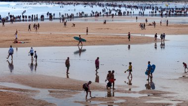Yaz mevsiminde Asturias 'taki Gijon plajının panoramik manzarası. Dalgaların çekildiği ve birçok turistin tatilde olduğu deniz manzarası..