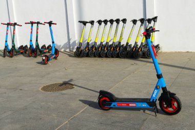 Şehirde dolaşmayı ve sürdürülebilir taşımayı kolaylaştırmak için sokakta park etmiş scooterlar..