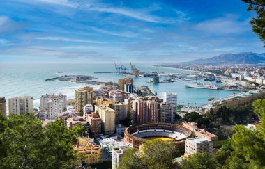 Endülüs 'ün Malaga şehrinin ön planda boğa güreşi ve arka planda ticari liman manzarası.
