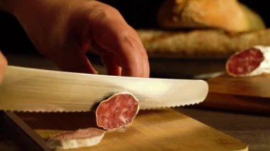 10 saniyelik Tam HD video kesim işlemi ahşap bir tahta üzerinde sosis ve arka planda odak dışı ekmek.