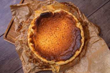 Kahverengi kağıt ve ahşap tahta üzerinde fırından yeni çıkmış bir cheesecake 'in durgun hayatının en güzel manzarası. Geleneksel İspanyol gastronomisi kavramı.