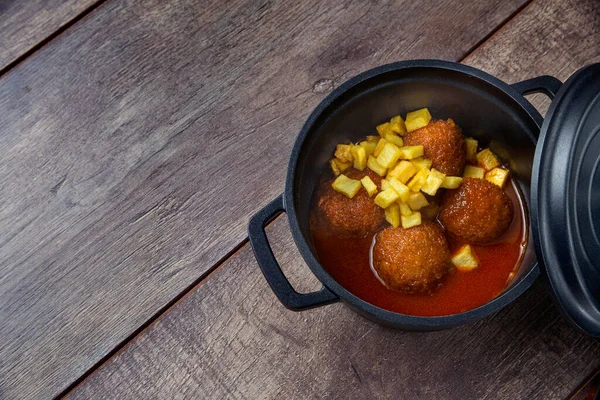 Tahta bir tahtanın üzerinde demir bir güveçte köfte ve domates sosuyla dolu bir hayat. Geleneksel İspanyol gastronomisi kavramı.