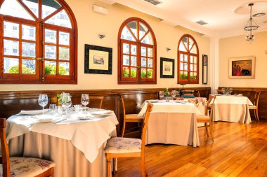 Sıcak ve dostane bir atmosferde masaları olan boş bir restoranın iç manzarası..