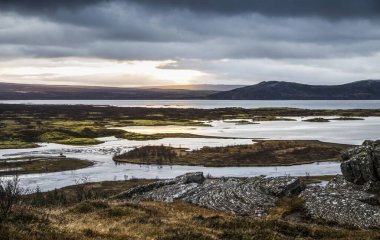 Kıyı bölgesinde gün batımında manzara bulutlu gökyüzü ve önünde güneş.
