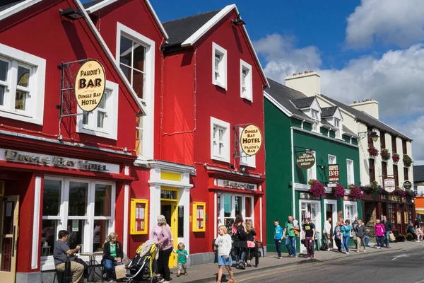 Yazın İrlanda 'nın Dingle kentindeki bir sokak manzarası, önünde bir bar ve otel ve kırmızı ve yeşil renkli tipik evler bulunuyor..