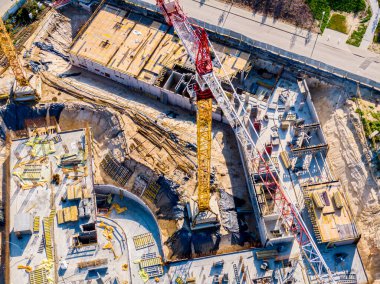 Çok katlı yeni binaların inşaatı. Şafak vakti inşaat vinci bir inşaat sahasında. İnsansız hava aracının görüntüsü. Sabah sisi ufukta.