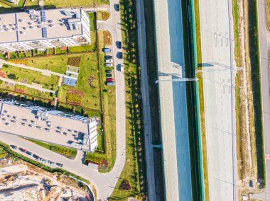 Kesişen yollar, evler, binalar, parklar, otoparklar, köprüler olan havacılık şehri manzarası. Helikopter insansız hava aracı atışı. Geniş Panoramik resim.