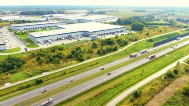 Otoyolun yanındaki lojistik merkezinin havadan görüntüsü. Otoyol boyunca arabalar gider. Ormanların yakınında. Otoyolda güneşli bir yaz günü. Teslimat merkezi