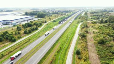 Otoyolun yanındaki lojistik merkezinin havadan görüntüsü. Otoyol boyunca arabalar gider. Ormanların yakınında. Otoyolda güneşli bir yaz günü. Teslimat merkezi