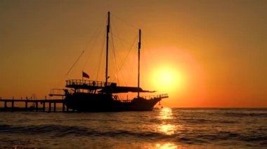 Yelkenli teknelerle deniz yüzeyinin üstünde renkli bir günbatımı. Su yüzeyine yansıyan güneş. Okyanusun üzerinde gün batımı. Deniz manzarası, yaz ve tatil konsepti