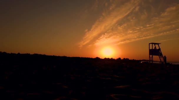 Tour de sauveteur Silhouette par le coucher du soleil. Les gens marchent. plage — Video