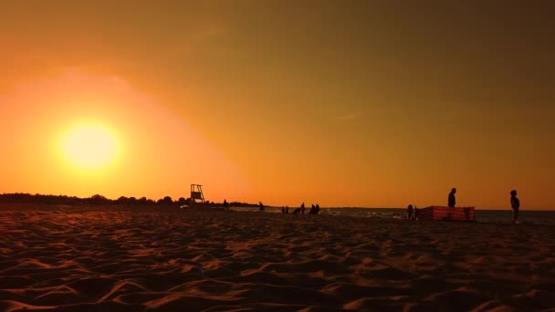 Torre de salva-vidas silhueta pelo pôr-do-sol. Pessoas a andar. praia — Vídeo de Stock