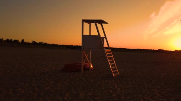 Средиземноморский пляж с деревянным спасательным креслом на закате, — стоковое видео