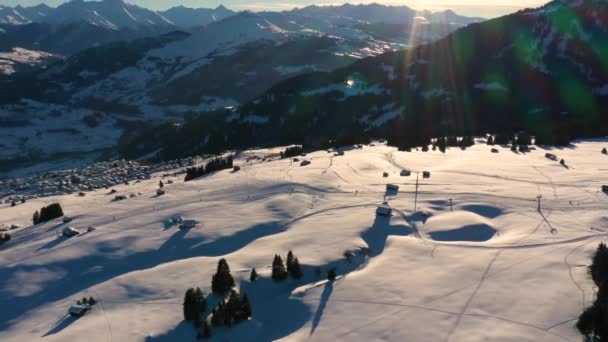 Вид с воздуха на лыжников на лыжных трассах. Золотой солнечный свет на закате в горах. Прекрасный солнечный вечер. — стоковое видео
