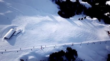 İHA 'dan kayak merkezinde panoramik üst görüntü. Kayak kaldırma asansörü kayakçıları ve snowboardcuları dağ eteklerindeki kar yamacında, bir sürü insan. UHD 4k video