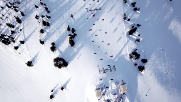 スキー場の丘の上の人々のスキーやスノーボードの空中ビュー。ドローンはスキーヤーの上を飛ぶ丘、アルプスの山々をスキー, — ストック動画