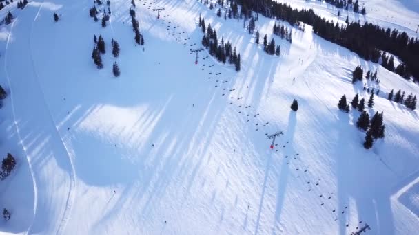 Panoramautsikt från drönare på kabelbanan i skidorten. Skidlift hiss transporterar skidåkare och snowboardåkare på snöig vintersluttning på fjällorten, många människor. UHD 4k video — Stockvideo