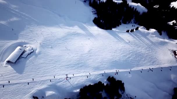 スキー場のケーブルウェイでドローンからのパノラマのトップビュー。マウンテンリゾートの雪の冬の斜面にスキーヤーやスノーボーダーを運ぶスキーリフトエレベーター、多くの人々。UHD 4kビデオ — ストック動画