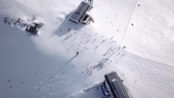 从空中俯瞰滑雪场,人们乘着滑雪板下山.库存录像。冬季，在雪地上滑过雪地或雪地，被茂密的森林环绕，旅行和运动 — 图库视频影像