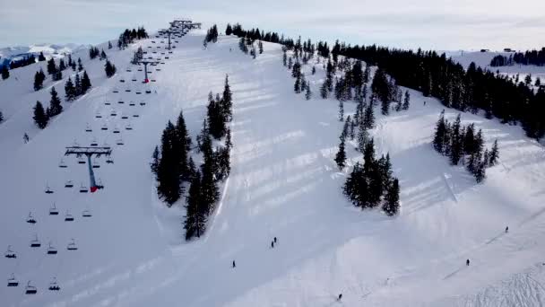 Vista superior panorámica desde el dron por cable en la estación de esquí. Ascensor de esquí que transporta esquiadores y snowboarders en la pista de invierno nevada en la estación de montaña, muchas personas. UHD 4k video — Vídeo de stock