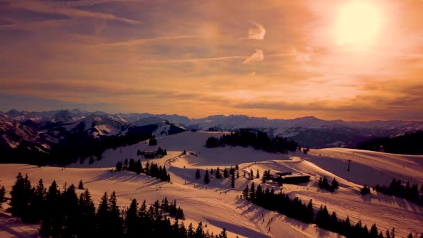 Picturesque white mountain slopes covered with pine forests and skiing pistes and moving chairlift in eavning Sunset aerial view. Alps — Stock Video
