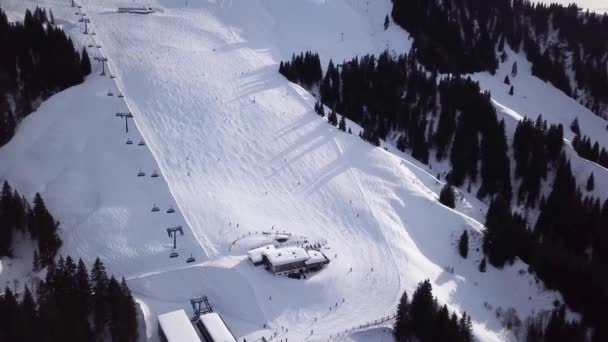 Uitzicht vanuit de lucht soepele beweging langs de skipistes in het skigebied. Prachtige besneeuwde bergen en blauwe lucht. Winterlandschap — Stockvideo