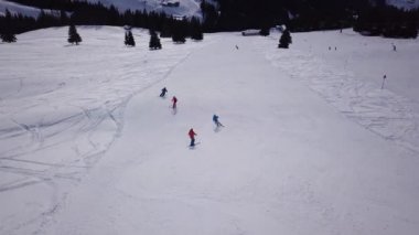 Tepenin aşağısında snowboard yapan insanların olduğu kayak merkezinin havadan görüntüsü. Stok görüntüleri. Kış mevsiminde sık ormanlarla çevrili beyaz kar üzerinde kayak pistinde uçmak, seyahat ve spor