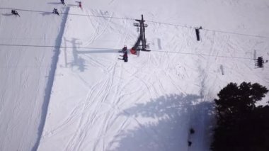 Kayak koltuğu kaldırma görüntüsü. Kayak merkezinde ulaşım için çok az insan var. Kayakçılar ve Snowboardcular Kar Kayağı yamacında. İnsansız hava aracı kabin ve kalabalık asansör kablosu üzerinde uçuyor.