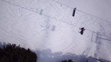 Kayak koltuğu kaldırma görüntüsü. Kayak merkezinde ulaşım için çok az insan var. Kayakçılar ve Snowboardcular Kar Kayağı yamacında. İnsansız hava aracı kabin ve kalabalık asansör kablosu üzerinde uçuyor.