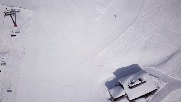 松林と太陽の山のスキーリゾートの空中。リフトで雪の斜面を滑り降りる。冬の自然景観。男性と女性の極端なスポーツ。積極的かつ健康的なライフスタイル。雪のトウヒの木 — ストック動画